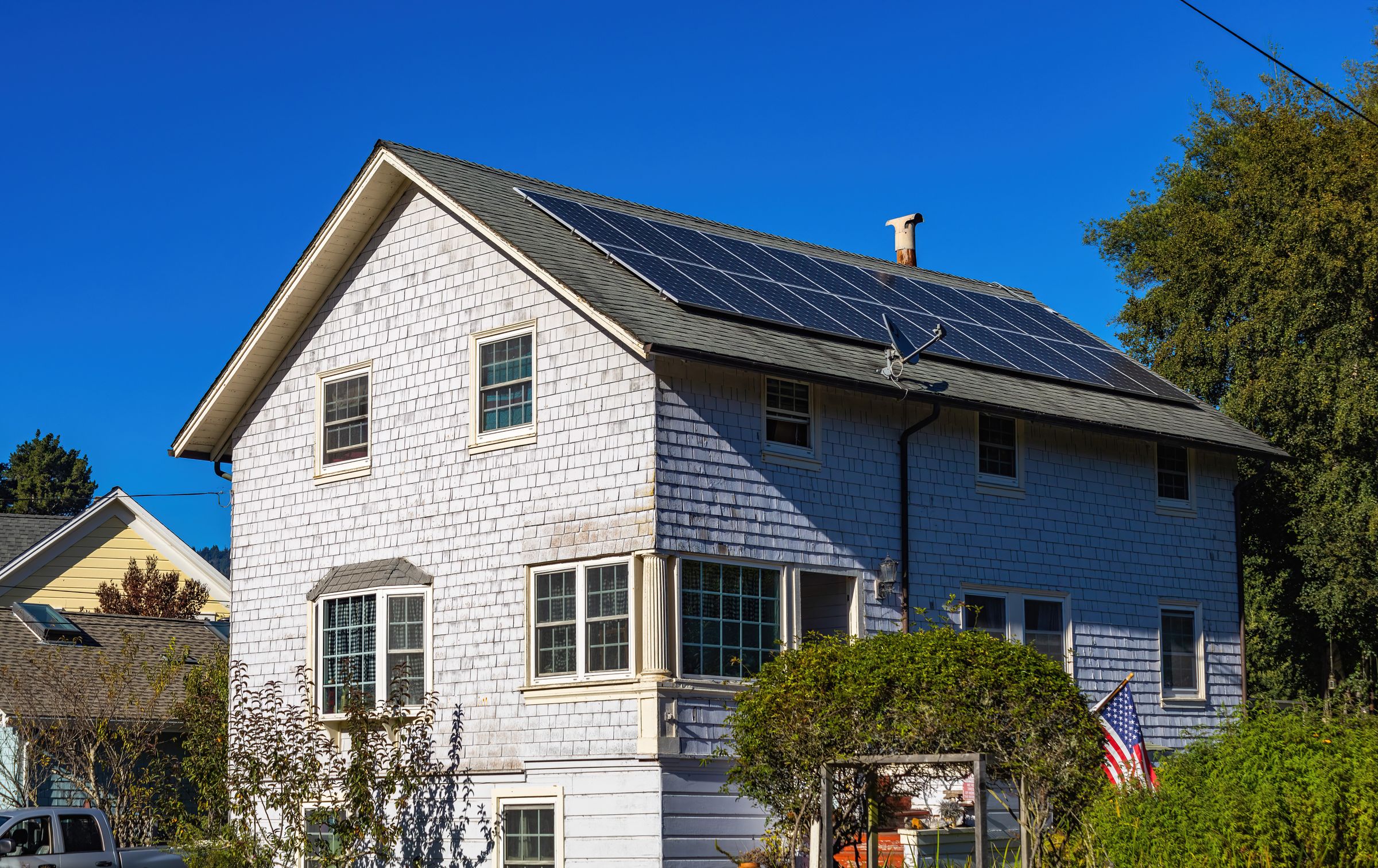A home with rooftop solar panels surrounded by trees